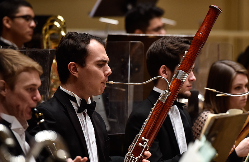 Students playing woodwind instruments (bassoons) in the orchestra.